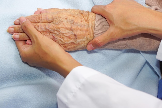 Il medico che tiene la mano di una donna anziana o anziana paziente anziana e incoraggia in ospedale