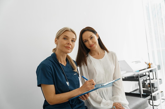 Il medico compila il modulo di referto medico dei pazienti durante l'appuntamento e guarda la telecamera