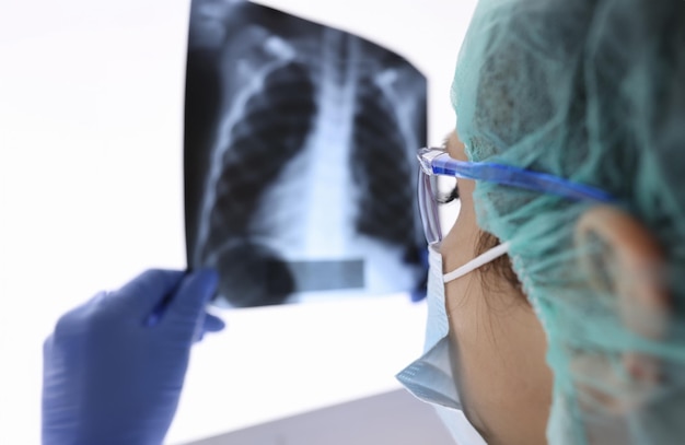 Il medico con maschera medica protettiva e guanti sta guardando una radiografia