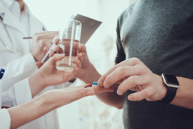 Il medico femminile sta dando le pillole all'uomo sportivo.