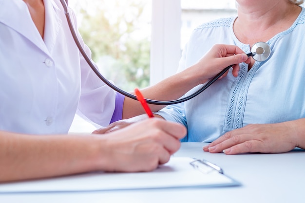 Il medico generale professionista ascolta il polmone e il battito cardiaco del paziente con lo stetoscopio durante una visita medica e una consultazione in ospedale