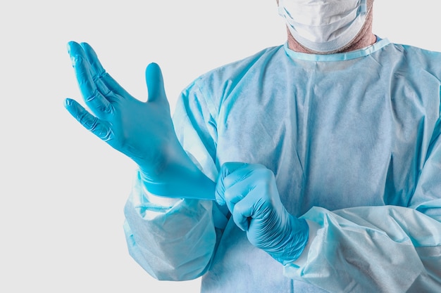 Il medico in una tuta protettiva indossa guanti medicali