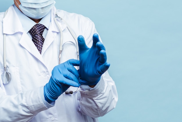 Il medico indossa guanti di gomma, assistenza sanitaria e medicina. Isolare su sfondo blu