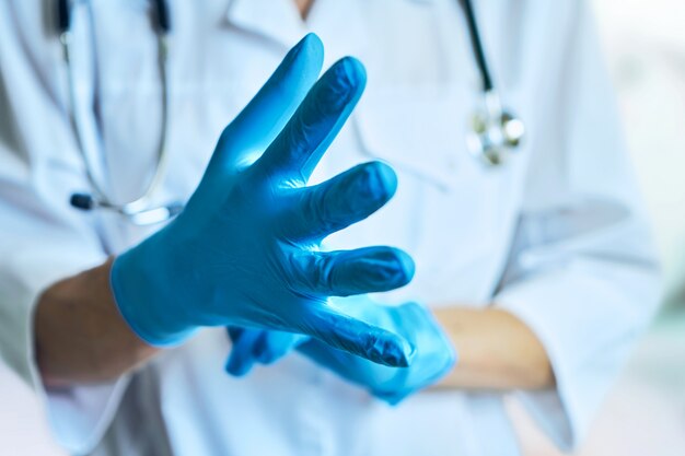 Il medico indossa guanti di gomma. isolato su uno sfondo blu chiaro
