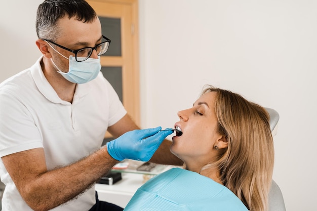 Il medico inserisce il portaimpronta e realizza il calco dei denti al paziente in odontoiatria prima dell'impianto dentale Procedura di creazione di corone e allineatori di protesi dentarie