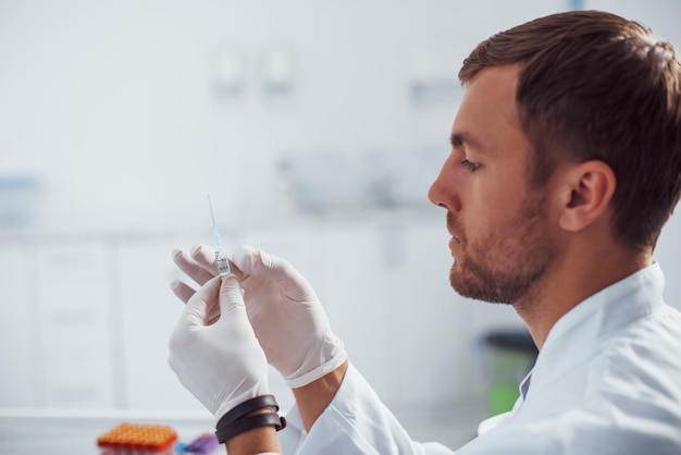 Il medico maschio con la siringa si sta preparando per il prelievo di sangue nella stanza della clinica.