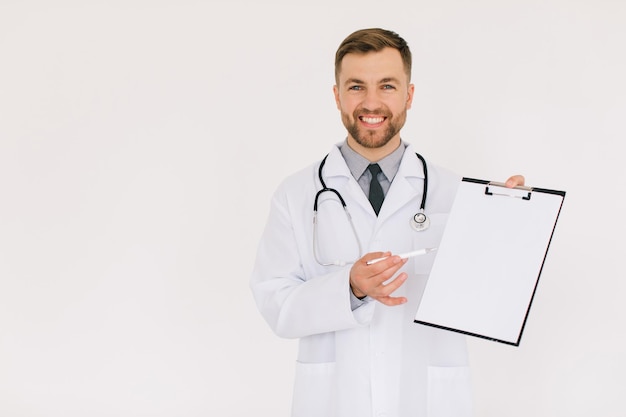 Il medico maschio felice con una cartella mostra qualcosa nello spazio della copia su una priorità bassa bianca