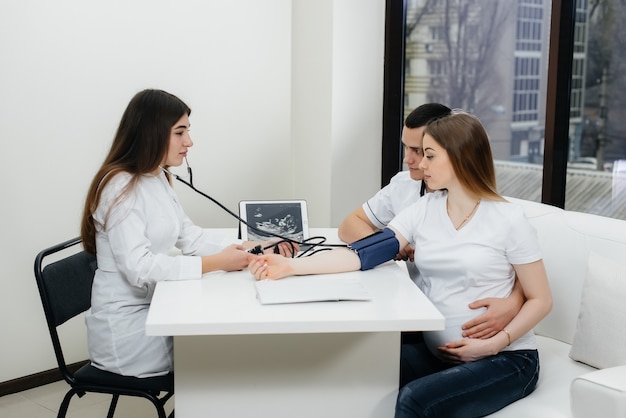 Il medico misura la pressione di una ragazza incinta nella clinica. Gravidanza e assistenza sanitaria