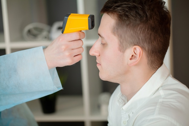 Il medico misura la temperatura del paziente con un termometro laser