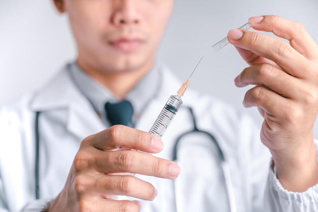 Il medico o lo scienziato porta una siringa e un vaccino contro la vaccinazione COVID19 e gli esperimenti di laboratorio Concetto di protezione contro il virus COVID19