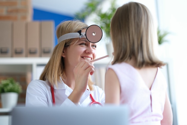 Il medico ORL conduce l'esame fisico della gola della bambina