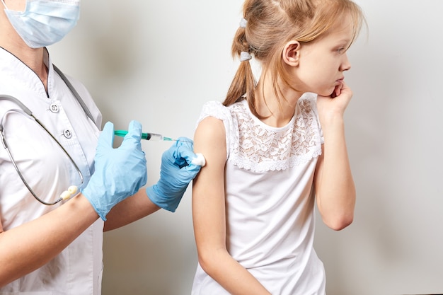 Il medico pediatrico tiene una vaccinazione per iniezione la ragazza. avvicinamento