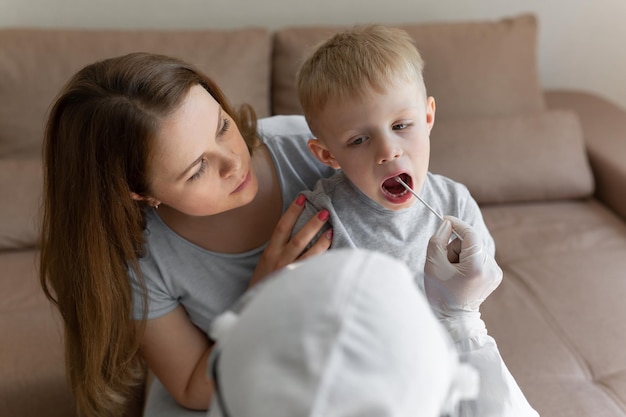 Il medico prende un cotton fioc dalla bocca del bambino per analizzare la mucosa della saliva