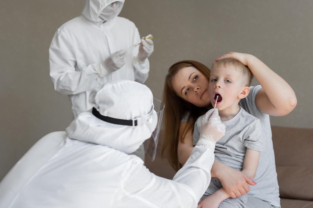 Il medico prende un cotton fioc dalla bocca del bambino per analizzare la saliva, la mucosa per i test del DNA, COVID-19, per determinare o la presenza di virus, epidemia di SARS-CoV-2, concetto di coronavirus.