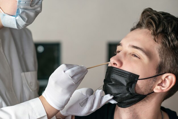 il medico prende un tampone dal test del DNA del naso del giovane Test PCR Assistenza sanitaria