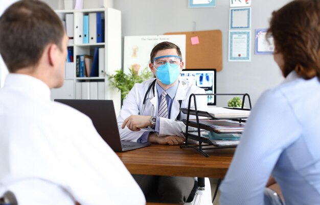 Il medico riceve i pazienti con una maschera medica protettiva