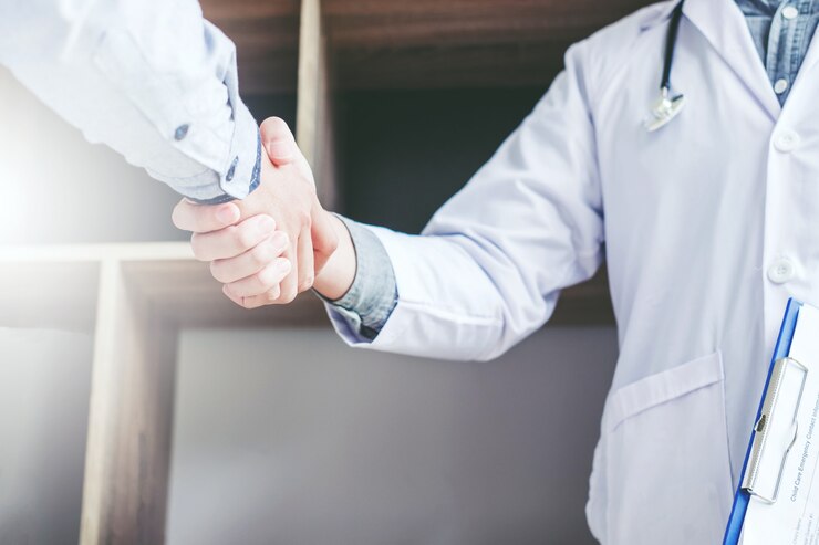 Il medico sicuro che stringe le mani con i pazienti parla nell'ospedale
