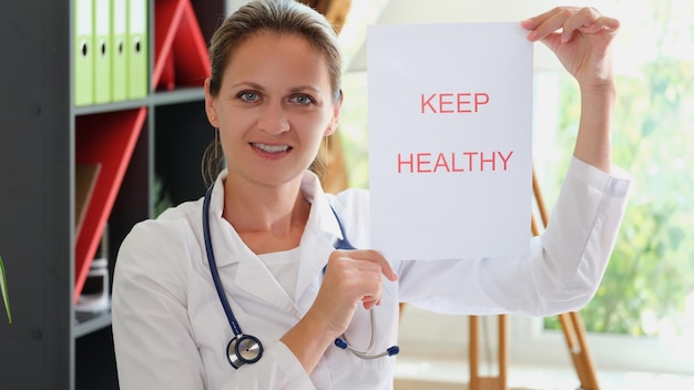 Il medico sorridente della donna mostra l'iscrizione mantiene il concetto di assicurazione sanitaria sana del paziente