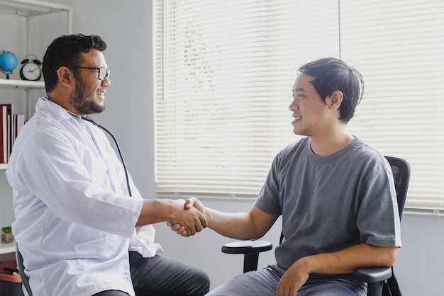 Il medico sorridente felice saluta il suo paziente stringendo la mano