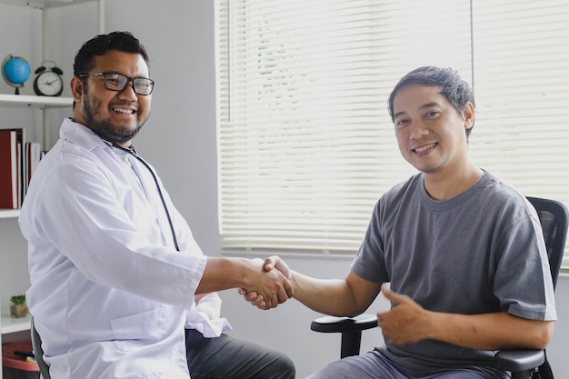 Il medico sorridente felice saluta il suo paziente stringendo la mano