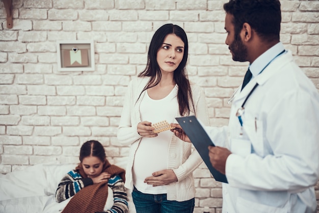 Il medico sta dando le pillole alla madre e alla figlia in gravidanza.