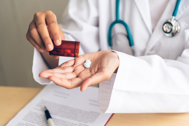 Il medico sta versando la medicina dalla bottiglia nel palmo