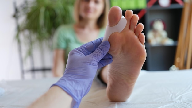 Il medico tiene il tutore per il dolore dell'alluce valgo nelle dita dei piedi può essere causato da una distorsione della tendinite ossea rotta