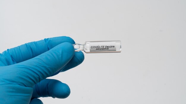 Il medico tiene in mano il vaccino contro il coronavirus COVID 19, il campione di sangue infetto nella provetta, l'iniezione di vaccino e siringa da utilizzare per la prevenzione, l'immunizzazione e il trattamento da COVID-19