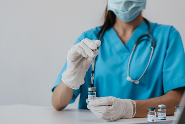 Il medico tiene una siringa con un ago in una mano e un contenitore con il vaccino COVID19 nell'altra