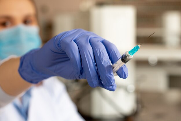 Il medico tiene una siringa in guanti blu prima dell'iniezione.