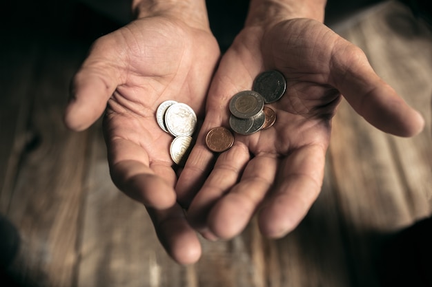 Il mendicante maschio passa alla ricerca di denaro sul pavimento di legno in un percorso pubblico