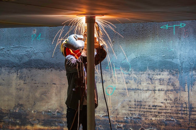 Il metallo del lavoratore maschio della saldatura fa parte della scintilla del flash della costruzione del fascio del carro armato del tetto della piastra del macchinario all'interno degli spazi ristretti