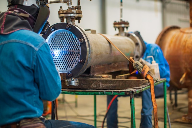 Il metallo riparato maschio del lavoratore dell'argon dell'arco di saldatura sta saldando le scintille riparazione industriale della costruzione