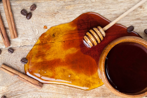 Il miele d'api fresco versato su una tavola versato in un piatto di legno e il miele di miele versato su una tavola di legno