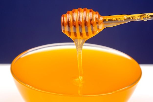 Il miele fresco e profumato gocciola da un cucchiaio in un piatto su uno sfondo colorato nutrizione vitaminica organica cibo da dessert