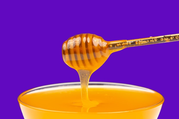 Il miele fresco e profumato gocciola da un cucchiaio in un piatto su uno sfondo colorato nutrizione vitaminica organica cibo da dessert