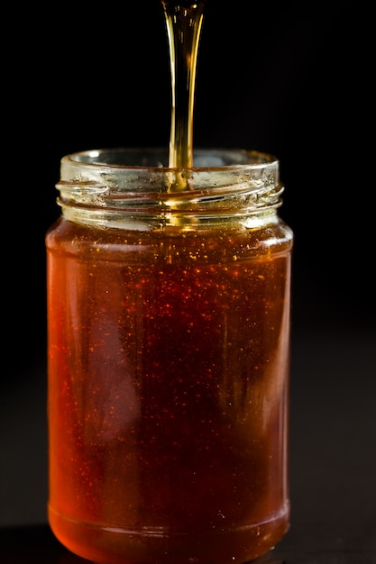 Il miele gocciola in un barattolo di miele