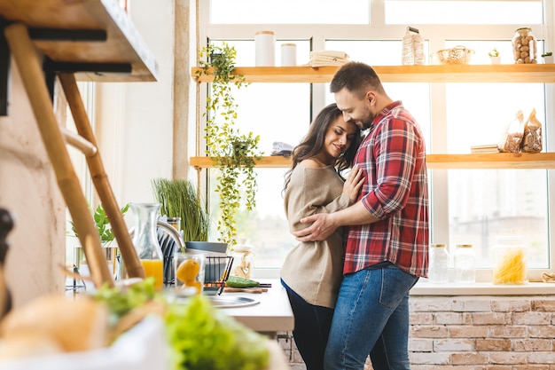 Il miglior tempo libero è rilassarsi a casa insieme. Belle giovani coppie che cucinano cena mentre stando nella cucina a casa.