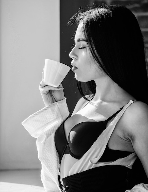 Il mio caffè mattutino e la routine del tempo tranquillo Donna sexy che beve un drink mattutino sano alla finestra Ragazza sensuale che si gode il suo caffè aromatico mattutino Il caffè la sveglia al mattino