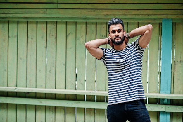 Il modello arabo alto bello dell'uomo della barba alla camicia spogliata ha posato all'aperto. Ragazzo arabo alla moda.