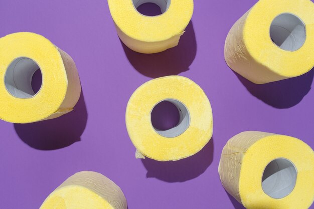 Il modello della carta igienica gialla luminosa rotola su fondo porpora.