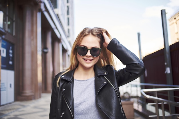 Il modello di donna felice in una giacca di pelle cammina per strada