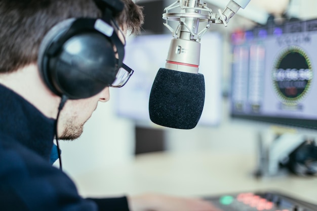 Il moderatore radiofonico è seduto in un moderno studio di trasmissione e parla al microfono