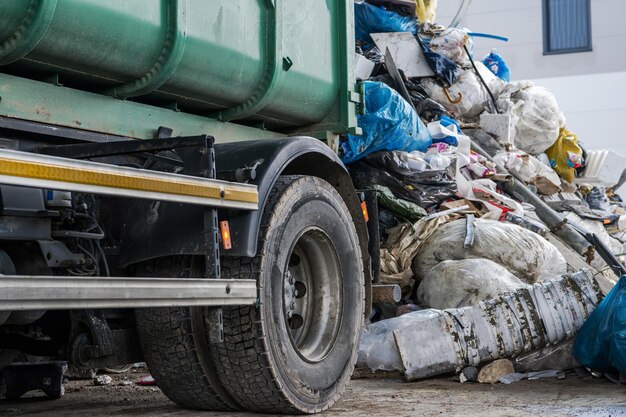 Il moderno camion della spazzatura da vicino e la pila di rifiuti di gestione dei rifiuti