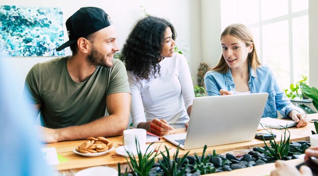 Il moderno team di avvio felice in abiti casual in ufficio o in uno spazio di co-working sta lavorando e discutendo loro piani e idee