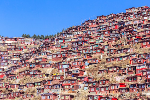 Il monastero rosso a Gar di Larung (accademia buddista) nel giorno e nel fondo del sole è cielo blu, Sichuan, Cina