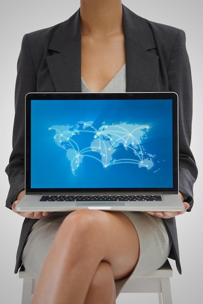 Il mondo non è mai stato così connesso Scatto in studio di una donna d'affari con in mano un laptop che mostra una mappa del mondo con le posizioni su di esso
