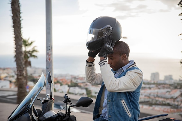 Il motociclista afroamericano indossa un casco mentre è seduto sulla sua moto