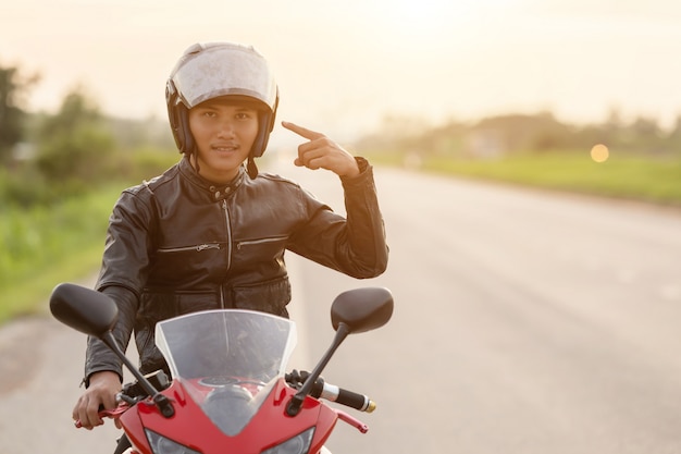 Il motociclista bello punta il dito sul suo casco