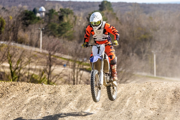 Il motociclista di motocross professionista guida attraverso il fumo e la nebbia sulla strada sterrata.